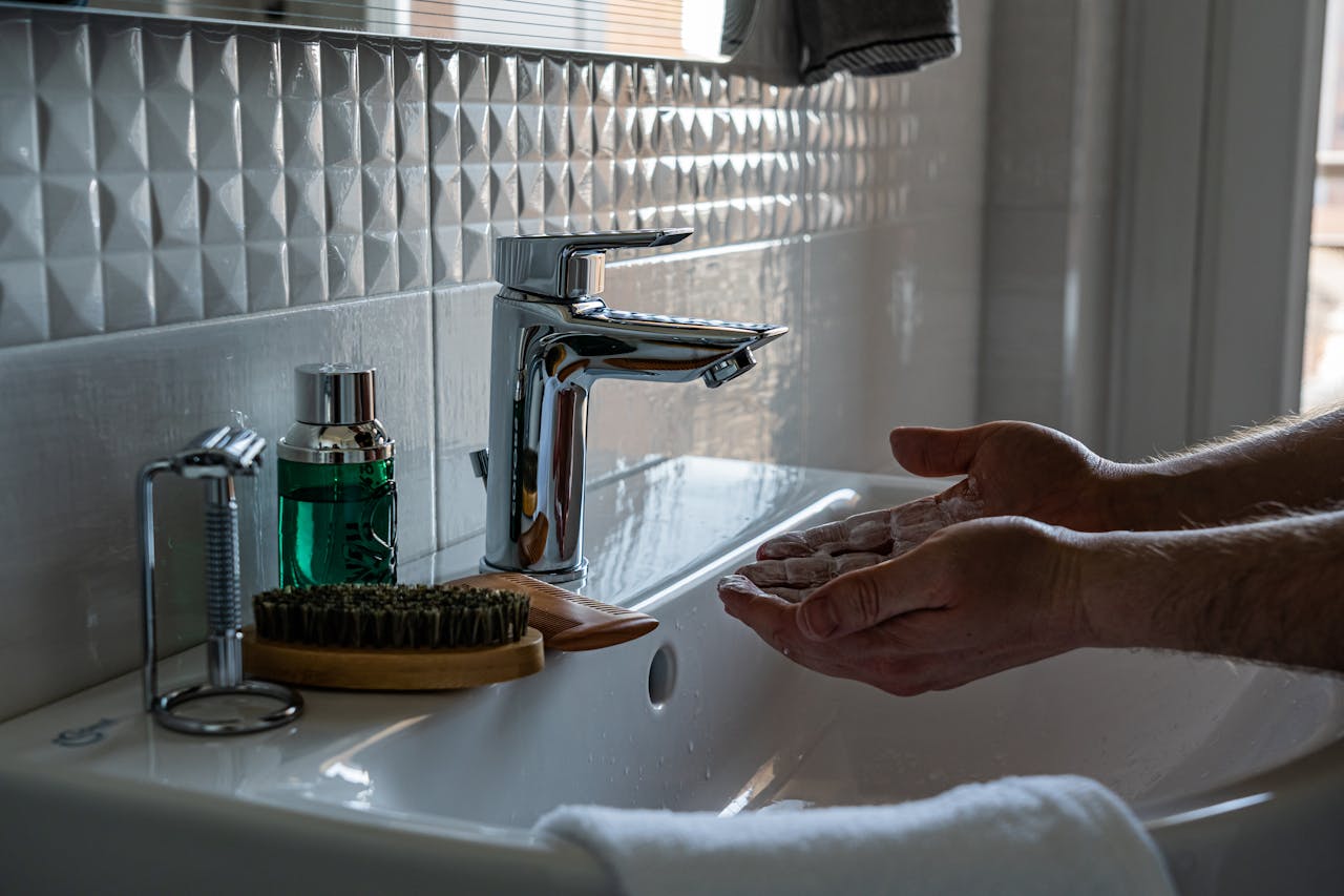 Close-up of handwashing with soap at a modern sink, emphasizing hygiene.